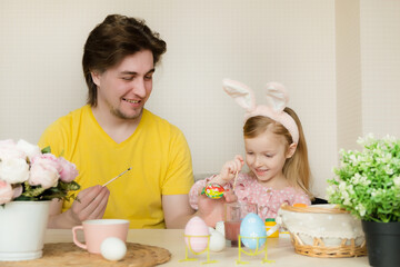 Easter, family, holiday and children concept. Father and daughter painting eggs. Happy family preparing for Easter
