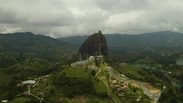 Drone Flies Away from Guatape Rock Revealing Lakes and Farmland Below