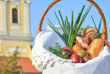Easter food basket blessing, tradition in Eastern Europe, basket with easter eggs, ham, bread and sprind onion, priest blessing