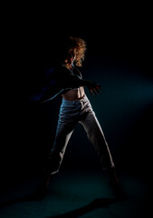 Young dancer doing acrobat moves isolated on dark wall