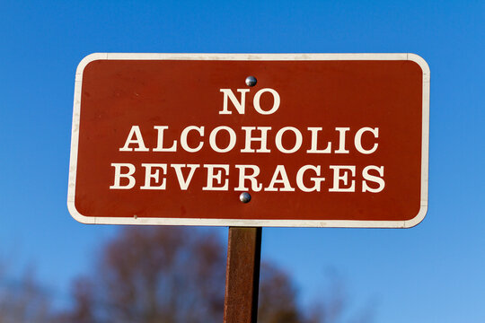 A brown metal plate with "No Alcoholic Beverages" notice on. This sign post is put on public areas and parks to restrict consumption of alcohol by visitors. A concept image with clear sky background