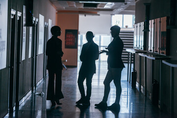 Fototapeta premium Silhouettes of business people standing in a corporate building.