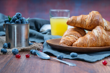 Freshly baked croissants with berries, jam on dark background, selective focus
