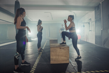 Four sportswomen are training glutes with multifunctional training in a sports club