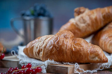 Freshly baked croissants with berries, jam on dark background, selective focus
