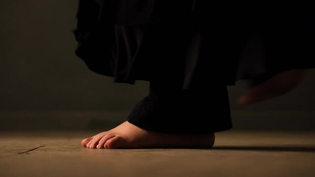 closeup of barefoot feets with black trousers moving, turn, jump and dance on a brown floor