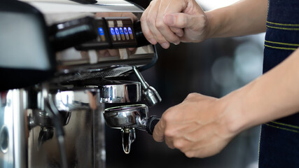 Close up of warm water rinsing at the pouring from coffee machine. A man barista preparing for pressing ground coffee for brewing espresso or americano in a cafe.