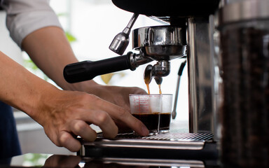 Close up hand. Making a cup of coffee in a coffee machine, the steam and the cup. Espresso maker machine with portafilter close up. Concept Coffee maker in cafe.