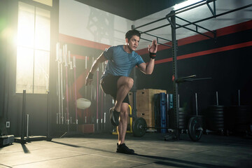 Obraz na płótnie Canvas Caucasian young man doing cardio exercise by high knees pose in gym.