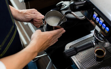 Close up hand holding Whipped cream with coffee. Making a cup of coffee in a coffee machine, the steam and the cup. Espresso maker machine with portafilter close up. Concept Coffee maker in cafe.