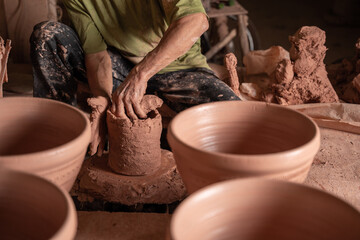 hand of men working on the potter's wheel. Hands sculpts a mortar from clay pot. clay ware handmade on the potter's wheel at thailand.