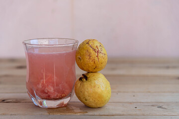 Glass with guava juice and fresh fruits on wooden background