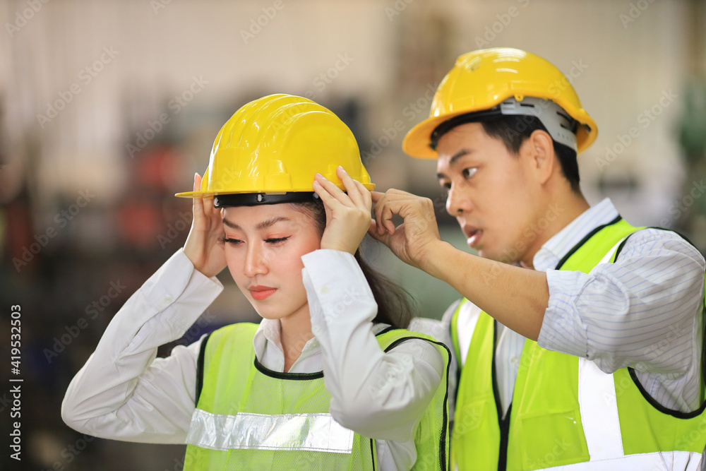 Wall mural industrial workers helping each other to wear hardhat while working inside the manufacturing factory