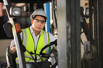 Asian industrial worker in full safety equipment operating the forklift inside manufacturing factory for distribution and logistics concept
