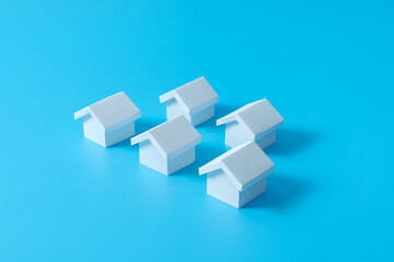 Fototapeta na wymiar Row of miniature 3D white houses on blue background for real estate property industry