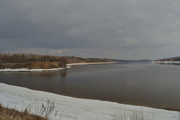 Floating Of Ice In Spring. Spring drifting of ice on the river against the background of a natural landscape and a cloudy sky. Volga River, Demino Park, Rybinsk.