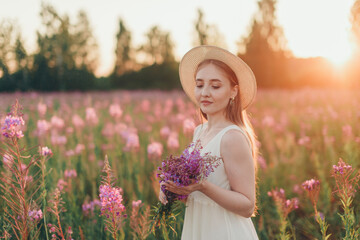 Fototapeta premium a happy girl with bouquet walks through a flower meadow. Love and spring blooming