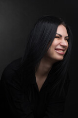 Fototapeta premium Studio portrait of a brunette in black clothes on a dark background