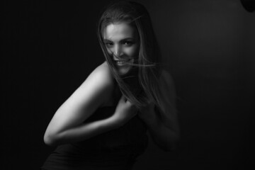 Fototapeta na wymiar black and white portrait of an adult woman in a studio on black background.