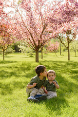 Naklejka na ściany i meble Two young boys sitting on grass in Spring