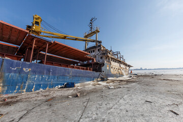 Environmental disaster at sea. A commercial small ship carrying oil sinks in ice within the city limits. The stern of the ship goes under water.