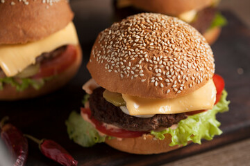 Juicy cheeseburger on a wooden board on a dark background