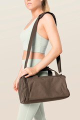 Sporty woman carrying brown duffle bag gym essentials studio shoot