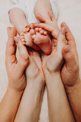 the baby's legs in the hands of the mother and father