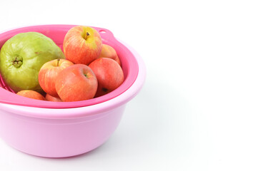 Bunch of apples and guava fruit in a plastic bowl over white background.