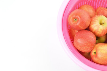Bunch of apple fruits in a plastic bowl over white background.