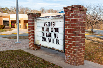 A large notice board in front of a public school in Maryland has a message to students who have been away due to COVID-19 pandemic. It reads welcome, we are joyful to have you back with us.