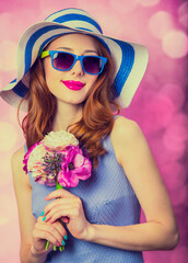 Redhead girl with flowers on pink background.