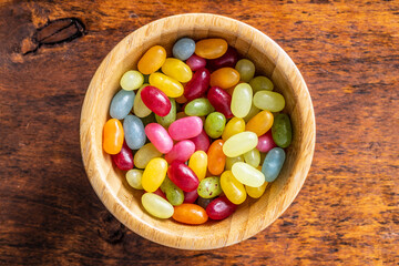 Sweet colorful jelly beans in wooden bowl.