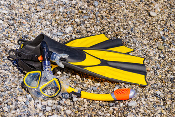 Flippers and snorkeling tube on sea shore