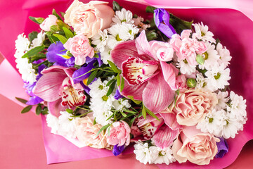 Mother's day, womens day or birthday background. Beautiful bouquet of blooming orchids, carnations and irises and spring greenery on a light pink background.