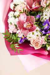 Mother's day, womens day or birthday background. Beautiful bouquet of blooming orchids, carnations and irises and spring greenery on a light pink background. Copy space.