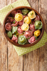 Italian pasta tortellini from colored dough close-up in a bowl on the table. vertical top view from above