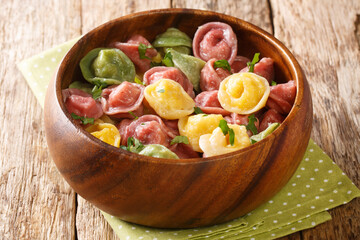 Homemade colored tortellini dumplings with various fillings close-up in a bowl on the table. horizontal
