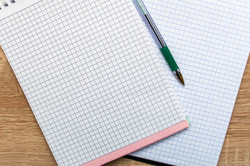 two open, clean notepads and a fountain pen lie on the table.