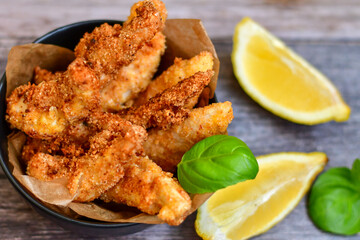 
 Crispy  deep fried home made    chicken strips Breaded  with  almond flour chicken  breast fillets  with chilly peppers and fresh   basil on wooden rustic background. Ketogenic diet food