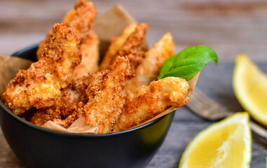 
 Crispy  deep fried home made    chicken strips Breaded  with  almond flour chicken  breast fillets  with chilly peppers and fresh   basil on wooden rustic background. Ketogenic diet food