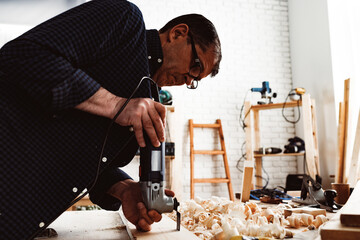 Carpenter cutting wood with electric jigsaw close up