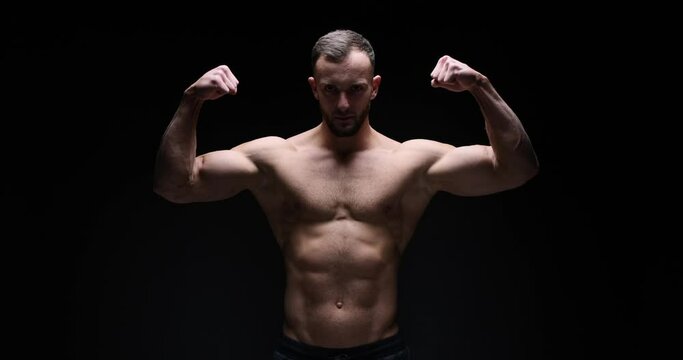 Shirtless muscular man flexing biceps over black background