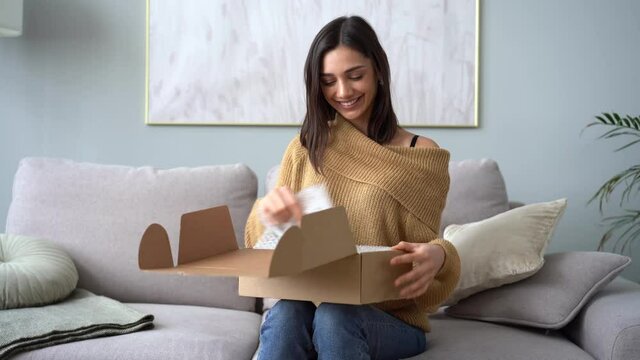Attractive Indian mixed-race woman customer opening parcel box at home