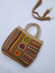 Image of colorful crochet bag made of leftover yarn. Isolated against white surface. Concept of creativity, something bright colorful, and utilization leftover things. Strap also appeared in frame. 