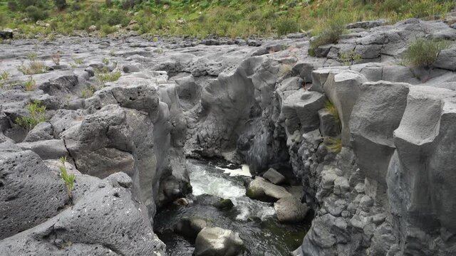 rocks in the watervolcanic rocks of Sicily nature split by a fault and smoothed by the impetuous flow of the flood waters of the Simeto river
