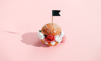 burger with a bouquet of flowers instead of cutlets on a pink background