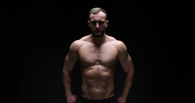 Shirtless muscular man flexing muscles over black background