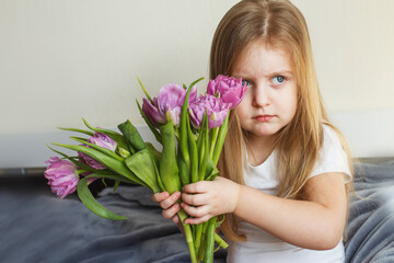 portrait of litlle girl with bouquet of flowers tulips in her hands