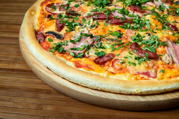 Pizza with cheese, bacon and herbs on a wooden plate. Close-up, selective focus
